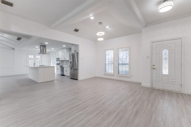 unfurnished living room with beam ceiling and light wood-type flooring