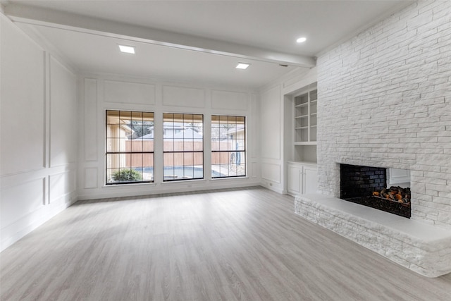 unfurnished living room with beamed ceiling, a multi sided fireplace, light wood-type flooring, and built in shelves