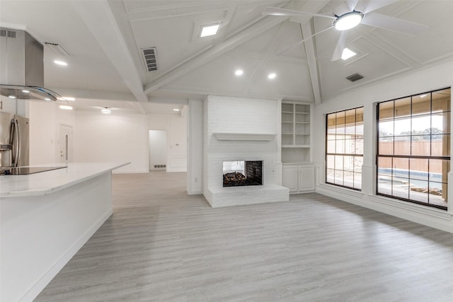 unfurnished living room with a fireplace, light wood-type flooring, ceiling fan, beam ceiling, and built in shelves