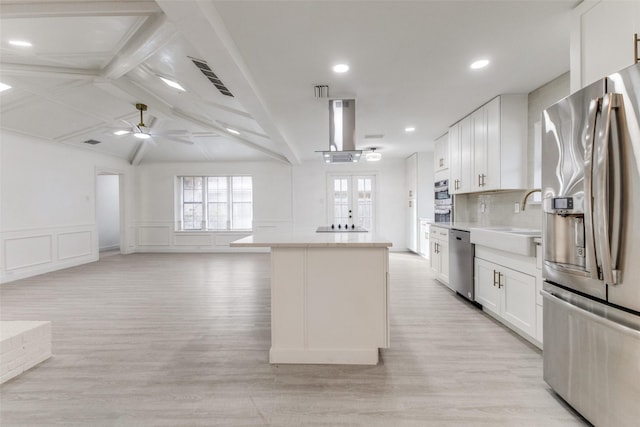 kitchen with sink, white cabinetry, stainless steel appliances, light hardwood / wood-style floors, and a kitchen island