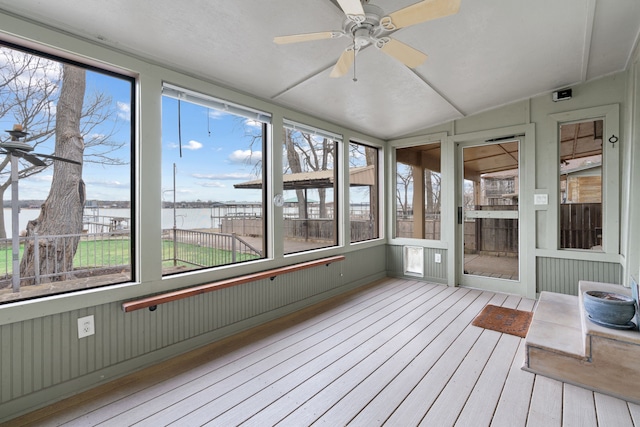 unfurnished sunroom featuring ceiling fan, a wealth of natural light, lofted ceiling, and a water view