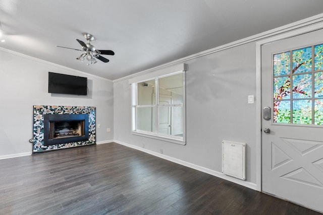 interior space with dark wood-type flooring, vaulted ceiling, ceiling fan, crown molding, and a tiled fireplace