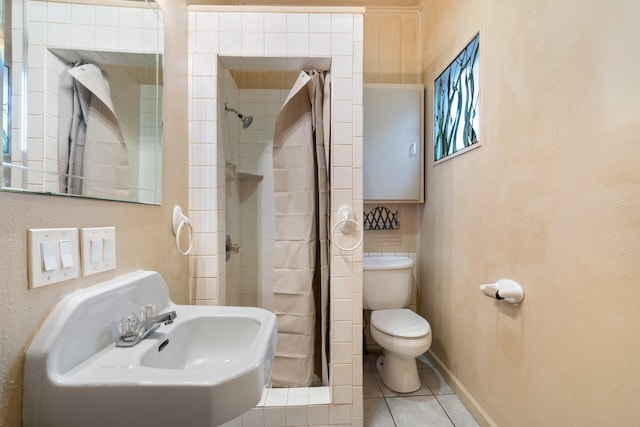 bathroom featuring sink, tile patterned floors, a tile shower, and toilet