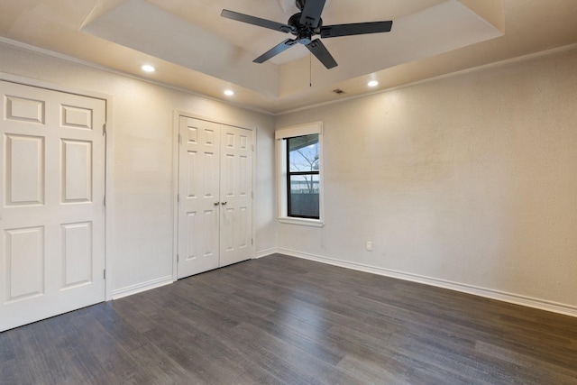 unfurnished bedroom featuring ceiling fan, dark hardwood / wood-style flooring, and a raised ceiling