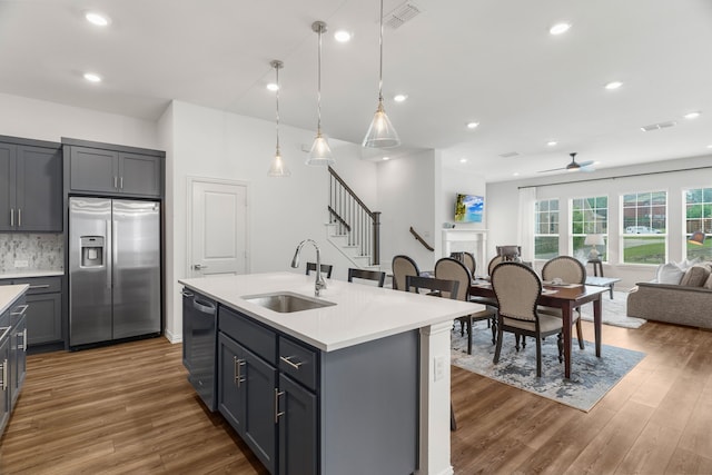 kitchen featuring a center island with sink, gray cabinets, appliances with stainless steel finishes, backsplash, and sink