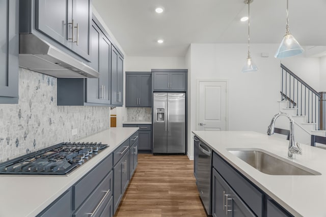 kitchen featuring stainless steel appliances, gray cabinetry, decorative backsplash, decorative light fixtures, and sink