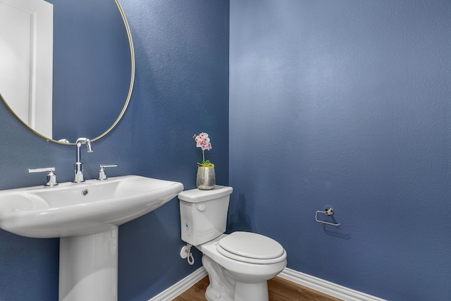 bathroom featuring toilet, wood-type flooring, and sink