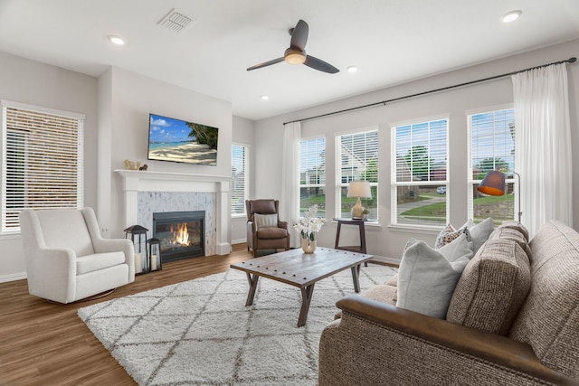 living room featuring ceiling fan, a tile fireplace, and hardwood / wood-style flooring