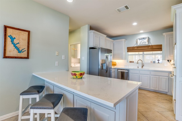 kitchen with white cabinetry, kitchen peninsula, stainless steel appliances, a kitchen breakfast bar, and sink