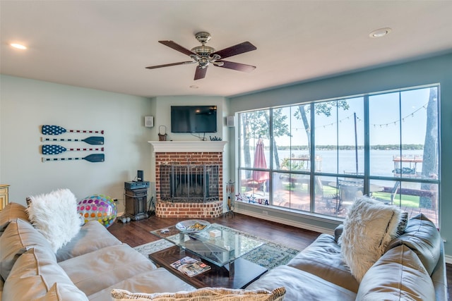 living room featuring ceiling fan, dark hardwood / wood-style flooring, and a brick fireplace