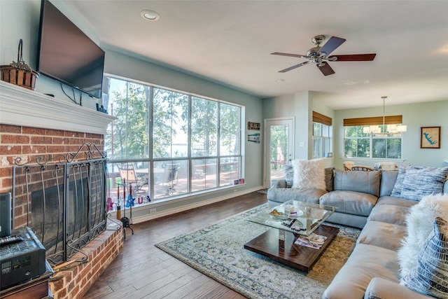 living room featuring ceiling fan, dark hardwood / wood-style flooring, a healthy amount of sunlight, and a fireplace