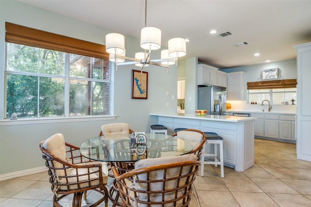 dining area with light tile patterned floors, plenty of natural light, sink, and an inviting chandelier