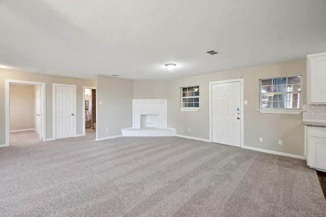 unfurnished living room featuring a brick fireplace and carpet floors