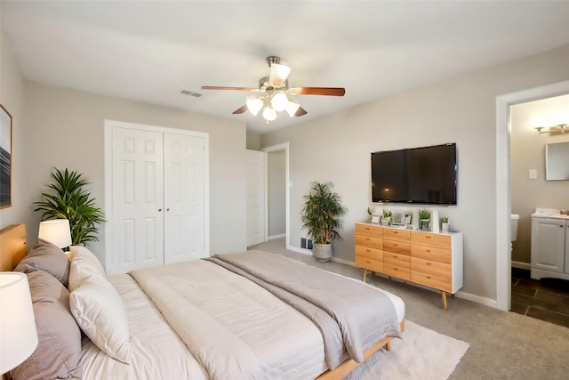 carpeted bedroom with ensuite bathroom, a closet, and ceiling fan