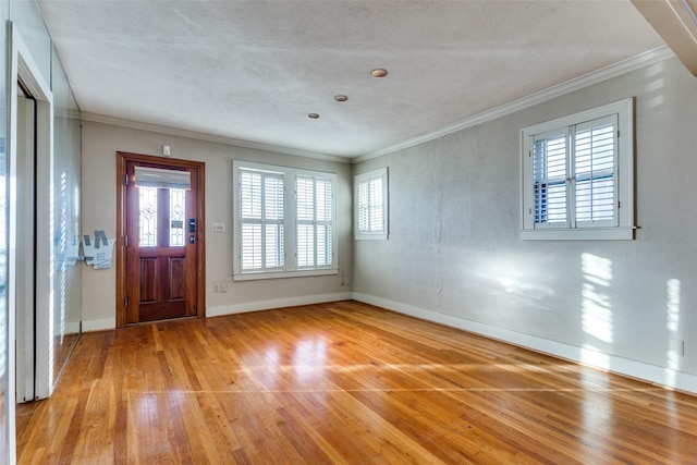 entrance foyer featuring light hardwood / wood-style flooring, ornamental molding, and a healthy amount of sunlight