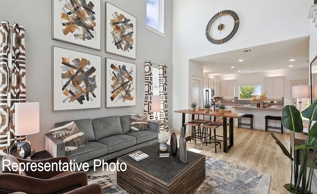 living room with a towering ceiling and light hardwood / wood-style flooring