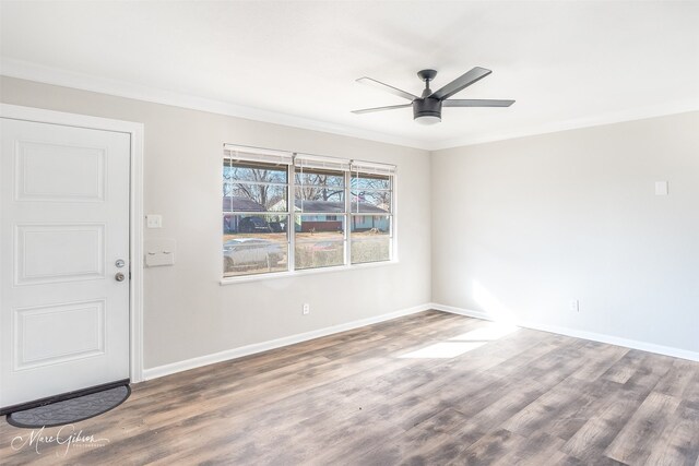 empty room with ornamental molding, dark wood-type flooring, and ceiling fan