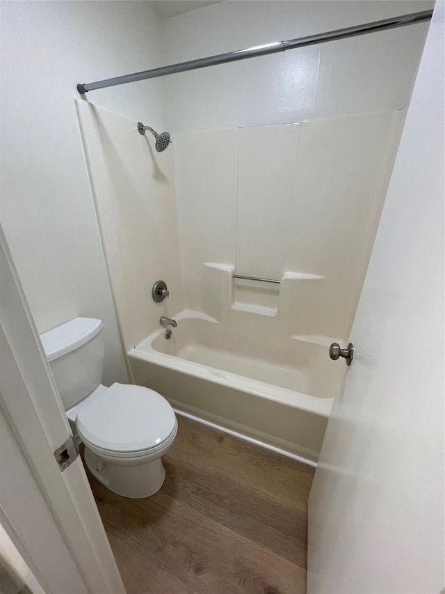 bathroom featuring hardwood / wood-style flooring, toilet, and shower / bathtub combination