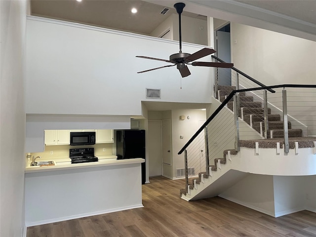 interior space featuring ceiling fan, hardwood / wood-style floors, a towering ceiling, sink, and crown molding