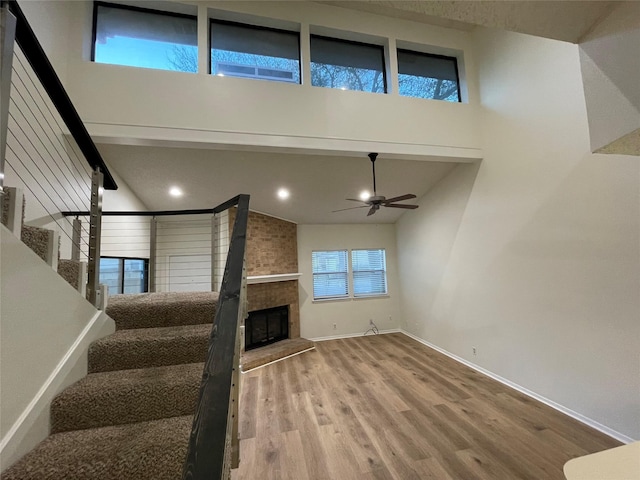 unfurnished living room with ceiling fan, a fireplace, hardwood / wood-style flooring, and high vaulted ceiling