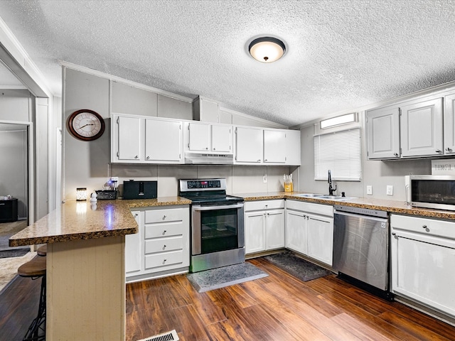 kitchen with kitchen peninsula, white cabinets, a breakfast bar area, and stainless steel appliances