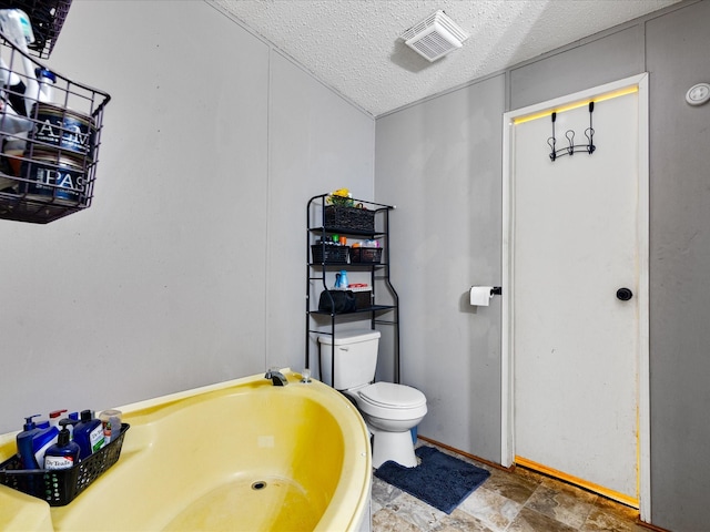 bathroom with toilet, a textured ceiling, and a bath