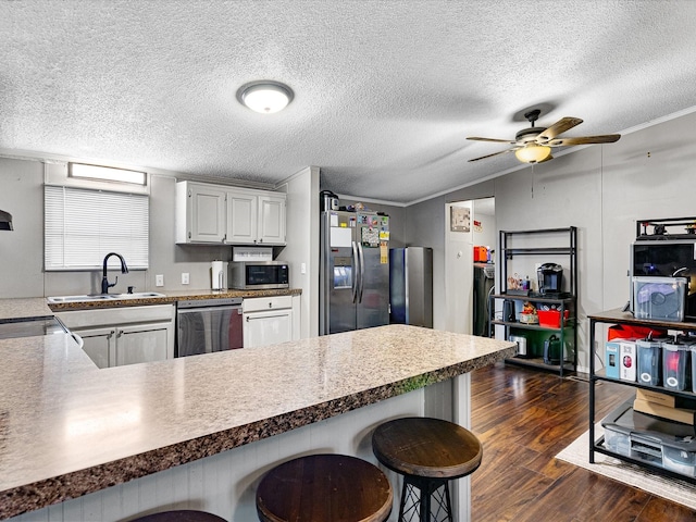 kitchen with a kitchen breakfast bar, sink, white cabinetry, and stainless steel appliances