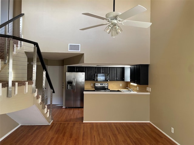 kitchen with stainless steel appliances, decorative backsplash, dark hardwood / wood-style floors, kitchen peninsula, and ceiling fan