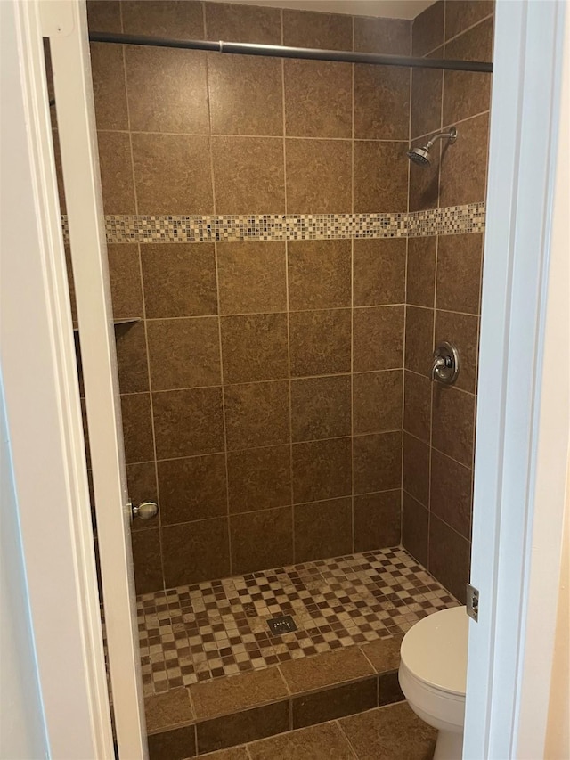 bathroom featuring toilet, tile patterned floors, and tiled shower