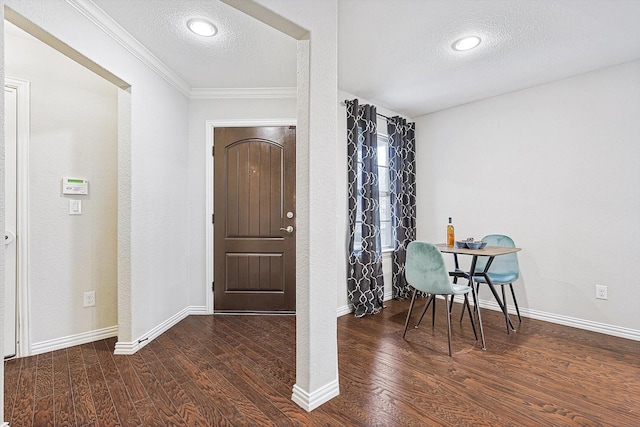 entryway featuring a textured ceiling, dark wood-type flooring, and crown molding