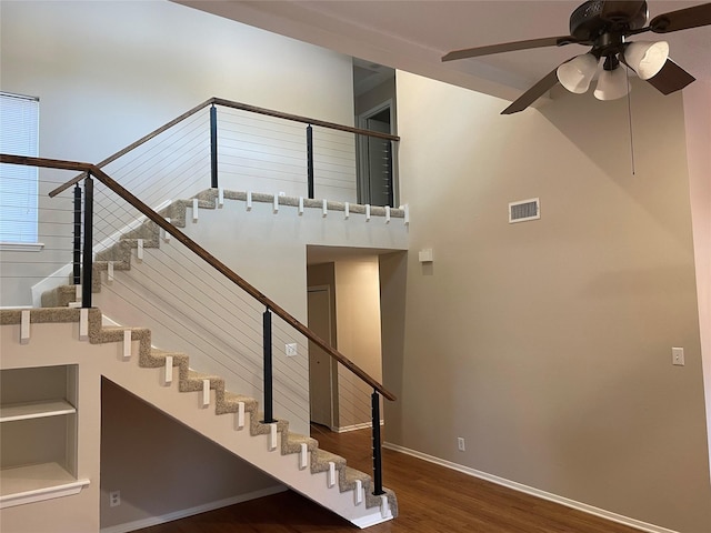 stairs featuring ceiling fan and hardwood / wood-style flooring