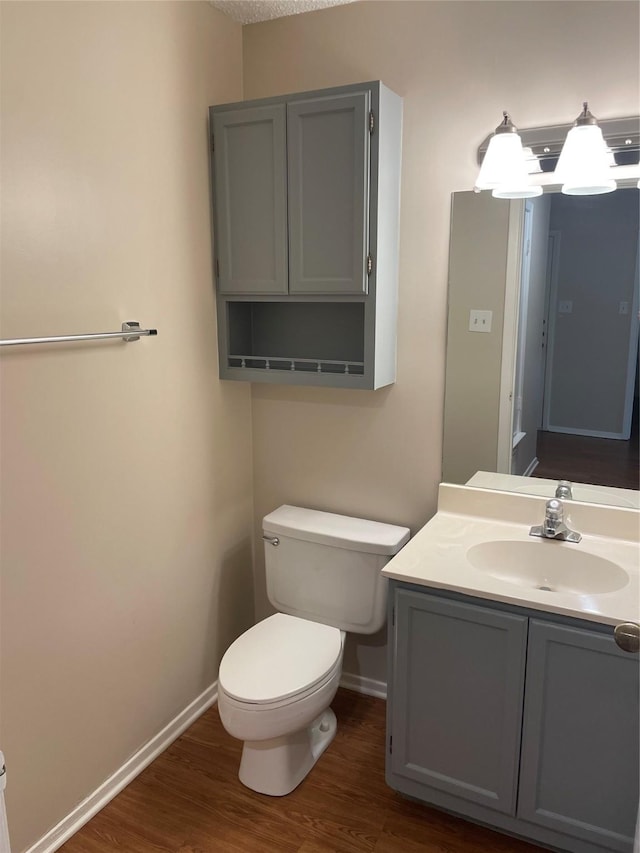 bathroom featuring toilet, vanity, and hardwood / wood-style floors