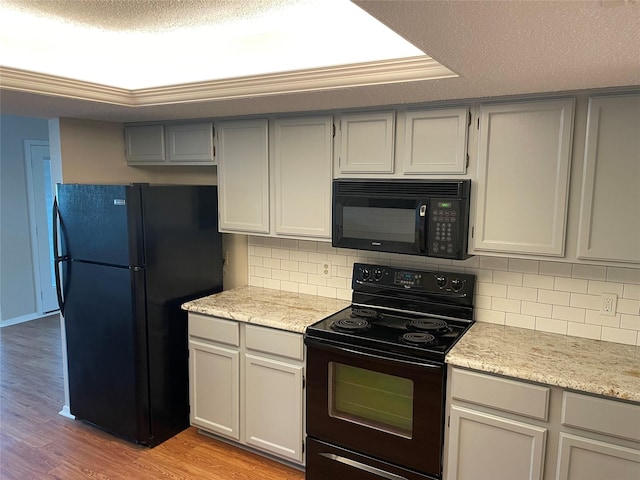 kitchen with a textured ceiling, black appliances, light hardwood / wood-style floors, backsplash, and light stone counters