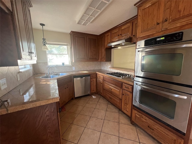 kitchen with pendant lighting, decorative backsplash, sink, stainless steel appliances, and light tile patterned floors