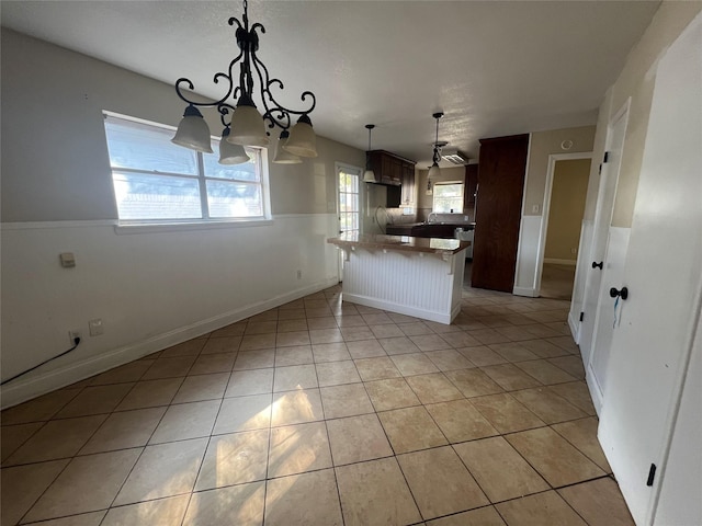 kitchen featuring a kitchen breakfast bar, hanging light fixtures, light tile patterned floors, and kitchen peninsula