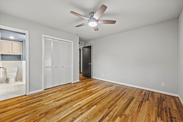 unfurnished bedroom with ceiling fan, ensuite bath, light hardwood / wood-style floors, and a closet