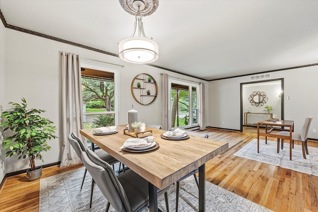 dining area with crown molding and light hardwood / wood-style floors