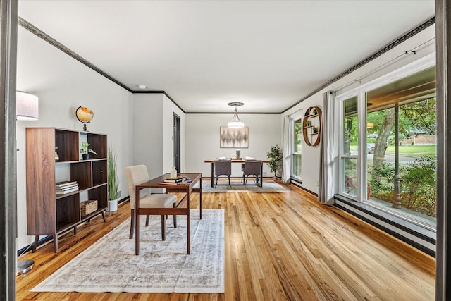 dining room featuring a baseboard heating unit, ornamental molding, and wood-type flooring