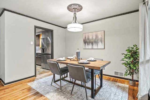 dining area with wood-type flooring and ornamental molding