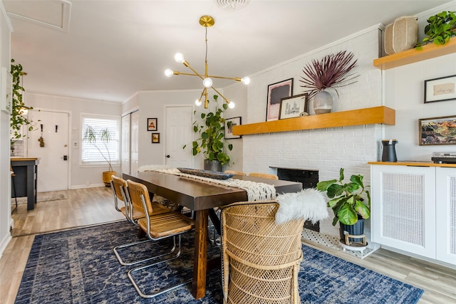 dining area with ornamental molding, an inviting chandelier, a fireplace, and light hardwood / wood-style floors