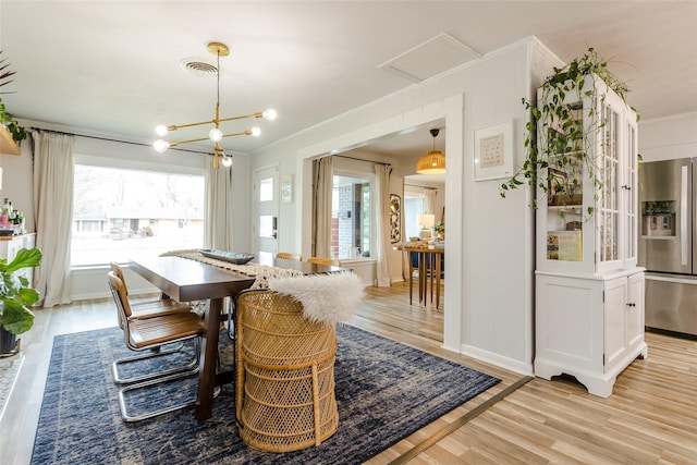 dining space featuring plenty of natural light, ornamental molding, and light hardwood / wood-style floors