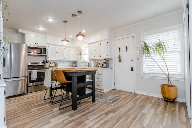 kitchen with appliances with stainless steel finishes, tasteful backsplash, white cabinetry, sink, and light wood-type flooring