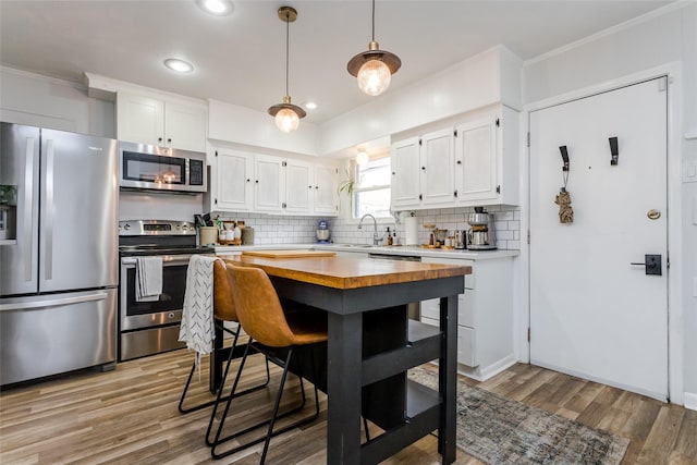 kitchen featuring white cabinetry, decorative backsplash, light hardwood / wood-style flooring, and stainless steel appliances