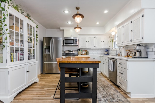 kitchen with appliances with stainless steel finishes, decorative light fixtures, tasteful backsplash, white cabinetry, and sink