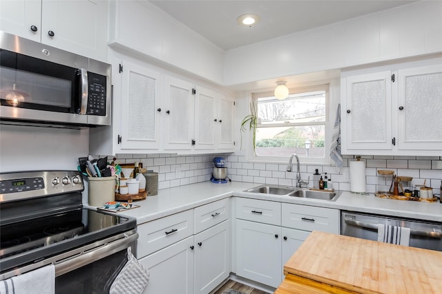 kitchen with white cabinetry, sink, decorative backsplash, and stainless steel appliances