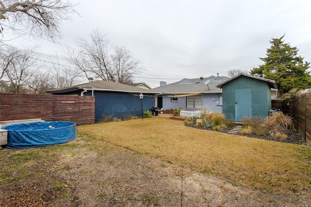 rear view of house featuring a yard and a shed