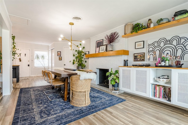 dining room with a notable chandelier, crown molding, a fireplace, and light hardwood / wood-style floors