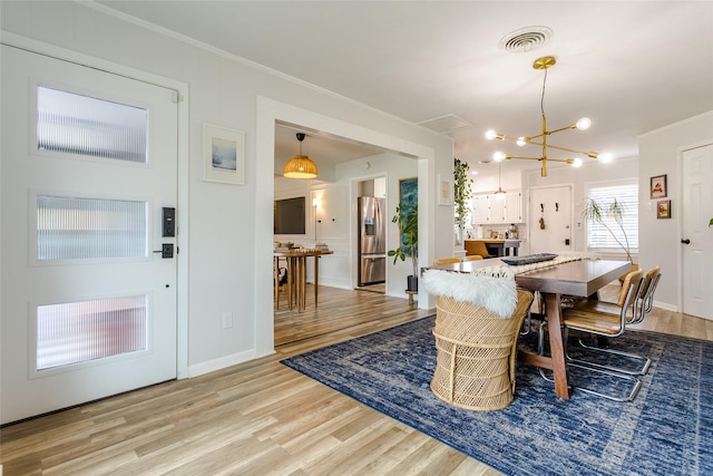 dining area featuring a notable chandelier, wood-type flooring, and ornamental molding