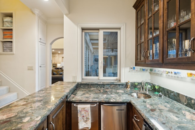 kitchen with dark brown cabinets, dark stone counters, and sink