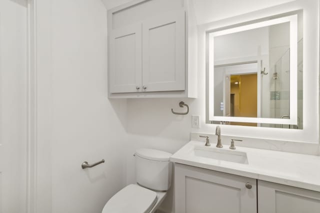 bathroom featuring toilet, walk in shower, and vanity